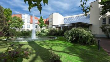 A courtyard with a fountain, lush greenery, and a building with solar panels.