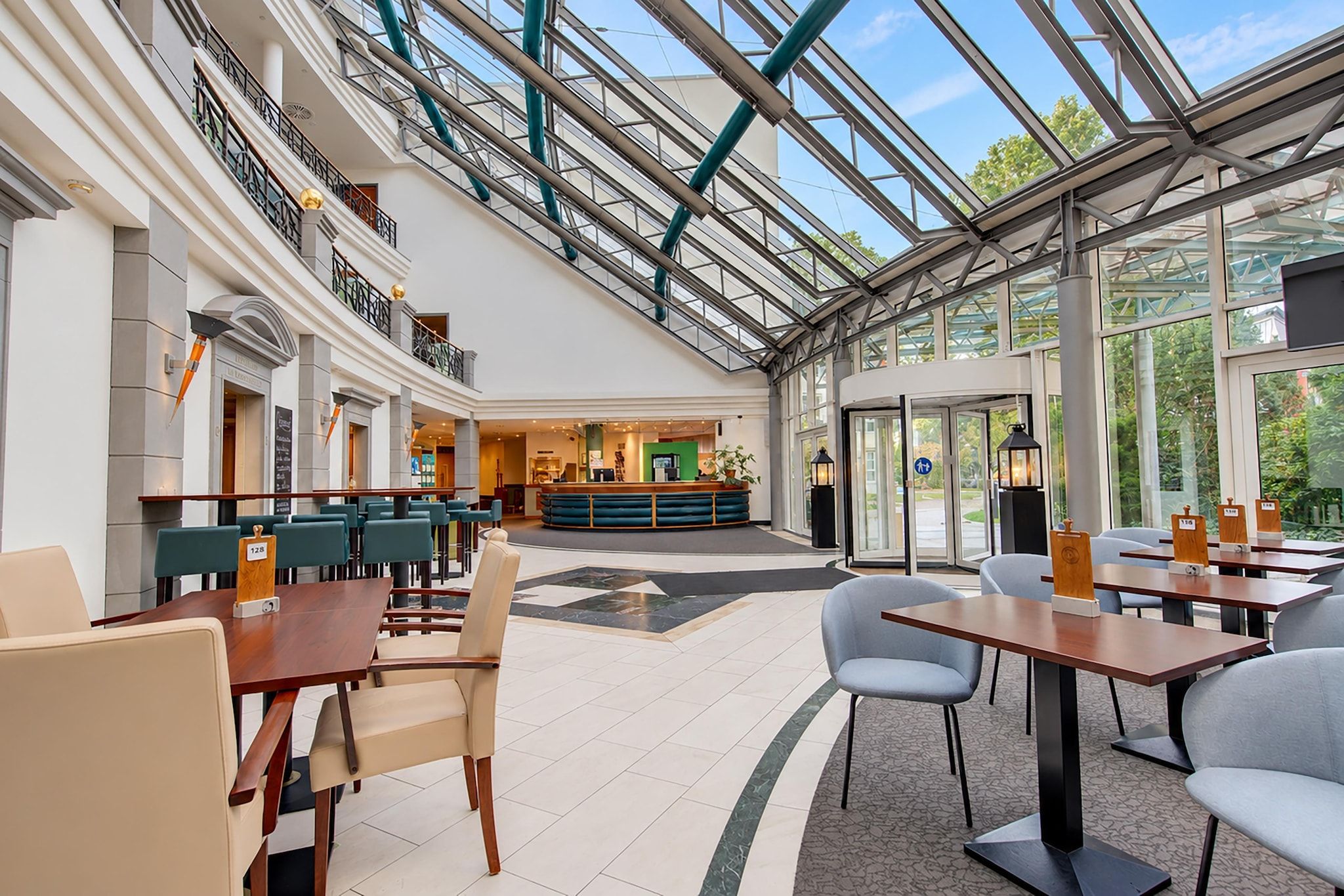Eine Hotelhalle mit Glasdecke, Sitzbereichen und einer Rezeption.