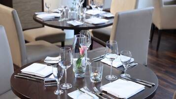 Mesa de comedor preparada con varias copas de vino, vasos de agua y cubiertos, lo que sugiere una disposición formal para comer.
