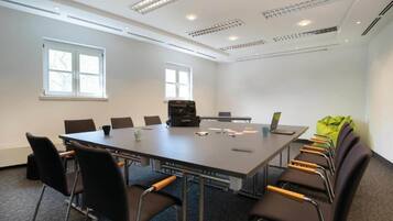 Ein Konferenzraum mit einem großen Tisch, Stühlen, einem Laptop und einer Aktentasche.