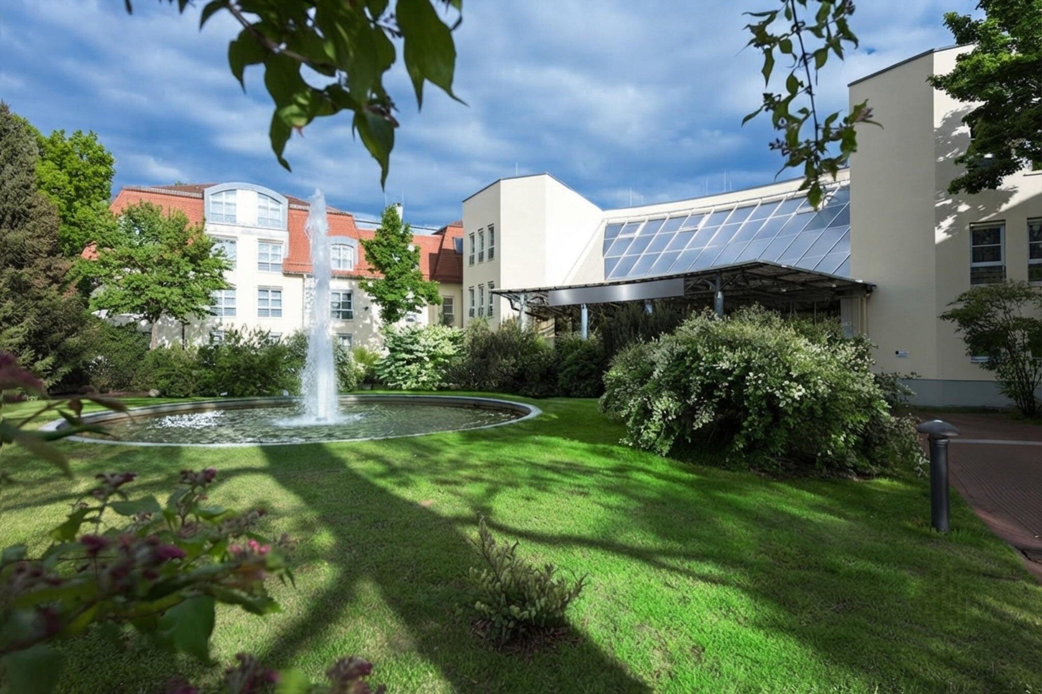 Une cour avec une fontaine, une végétation luxuriante et un bâtiment doté de panneaux solaires.