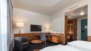 Ein Hotelzimmer mit Bett, Schreibtisch, Stuhl, Fernseher und Bad.