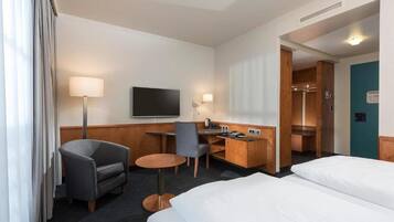 Ein Hotelzimmer mit Bett, Schreibtisch, Stuhl, Fernseher und Bad.