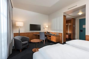A hotel room with a bed, a desk, a chair, a TV, and a bathroom. - Hotel Leipzig Superior Double Room (Leipzig)