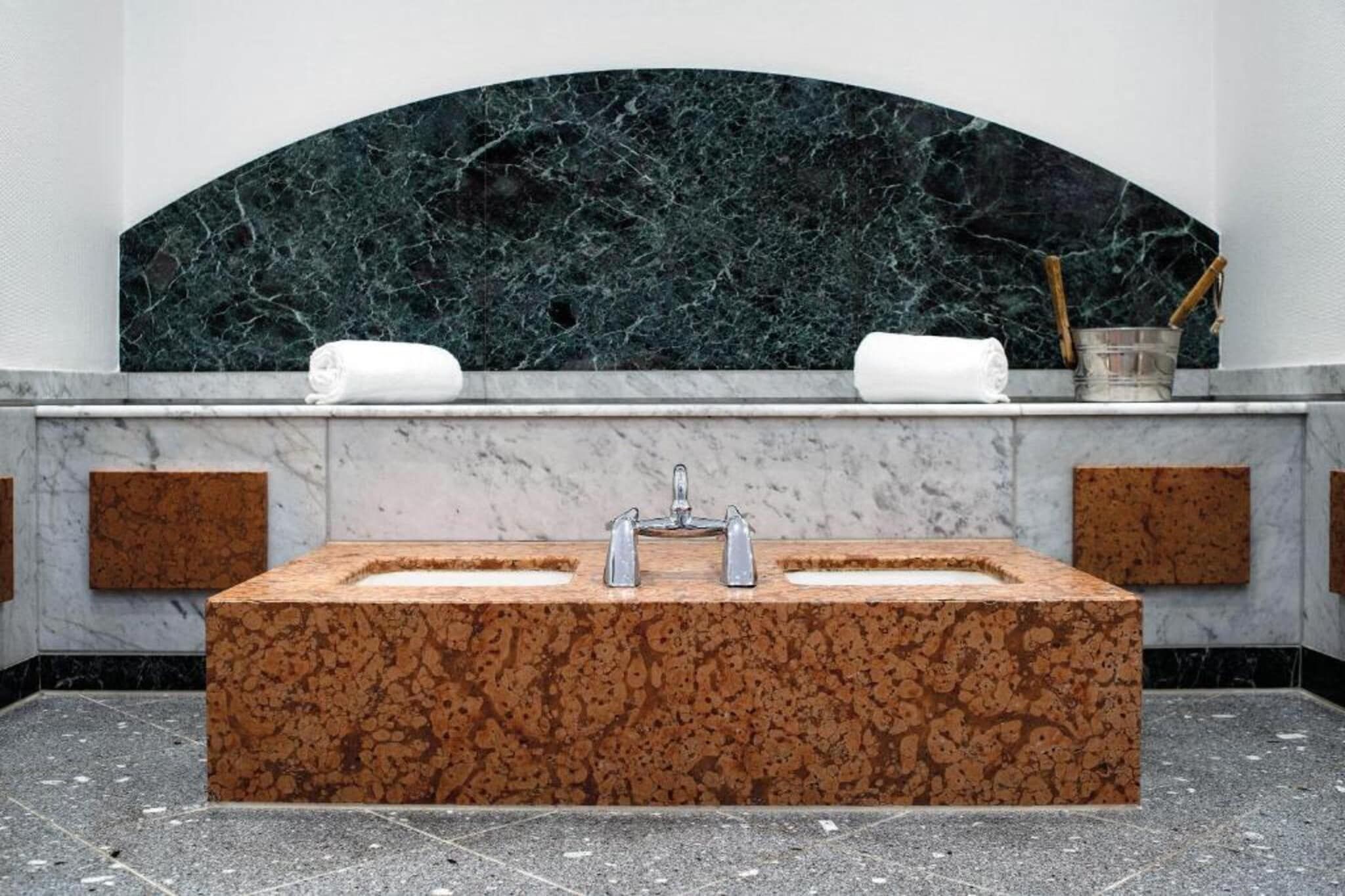 Ein Badezimmer mit einem rechteckigen Waschbecken, zwei Handtüchern und einer Marmorwand.