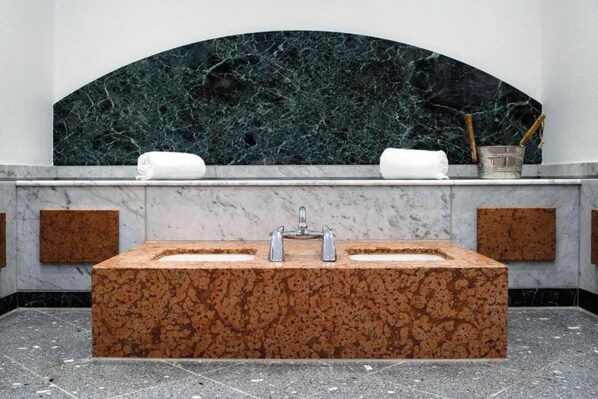 A bathroom with a rectangular sink, two towels, and a marble wall.