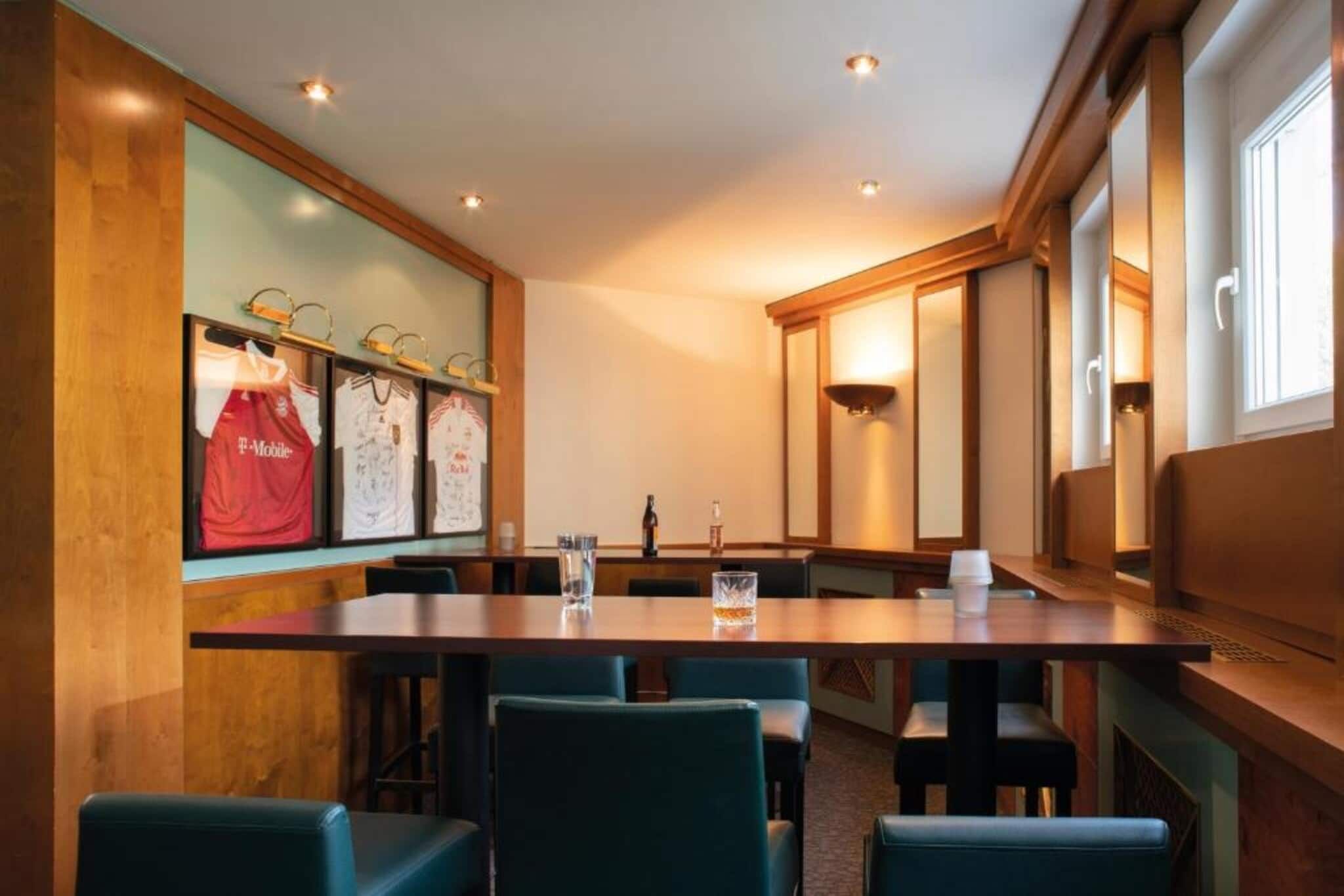 Ein Konferenzraum mit langem Tisch, Stühlen und gerahmten Sporttrikots an der Wand.