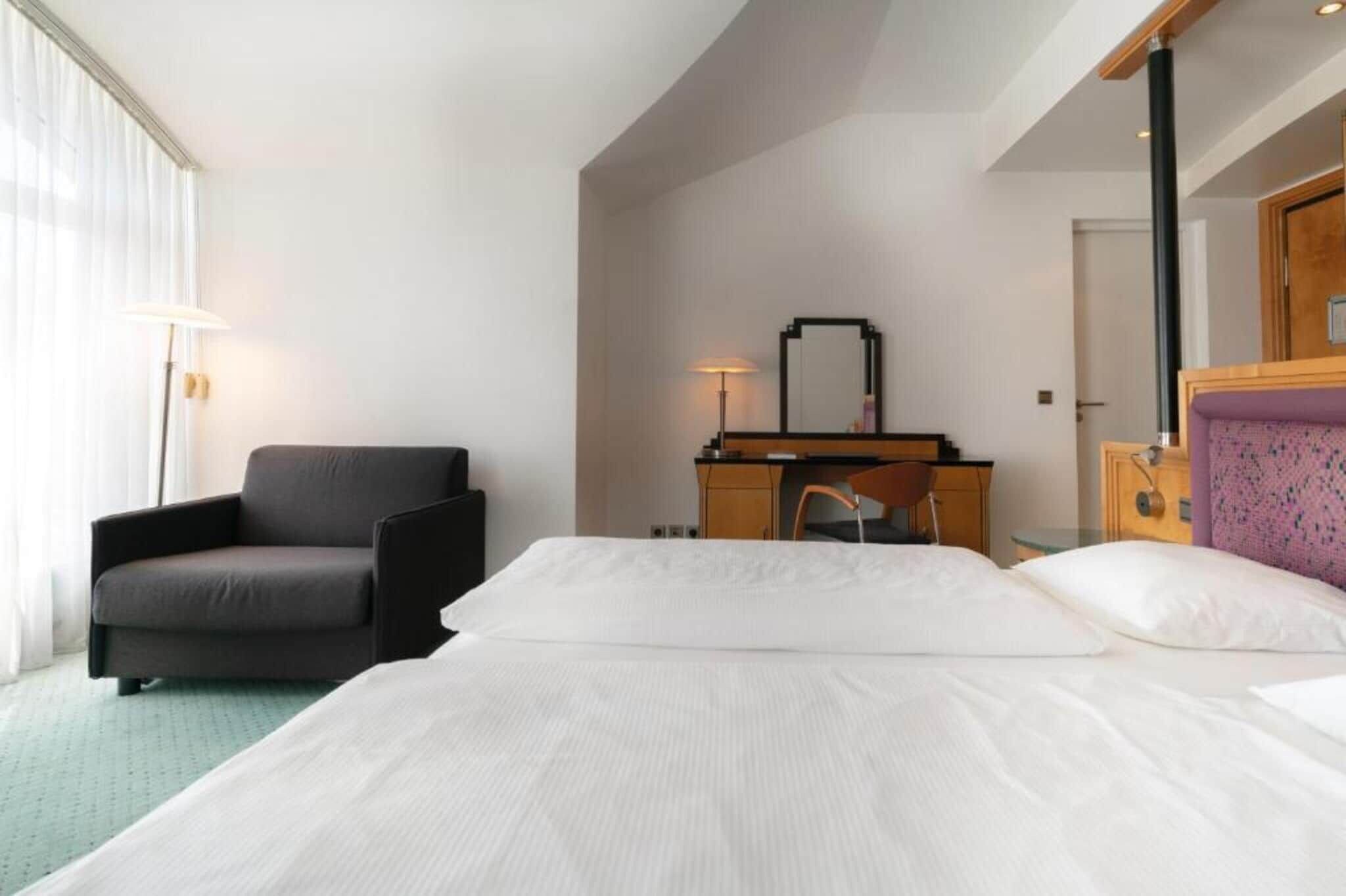 Ein Hotelzimmer mit Bett, Schreibtisch, Stuhl und Lampe.
