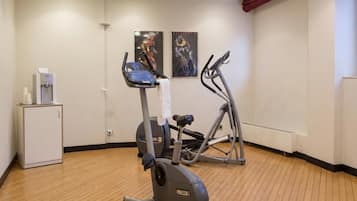 Een sportschool met trainingsapparatuur, een waterdispenser en twee posters aan de muur.