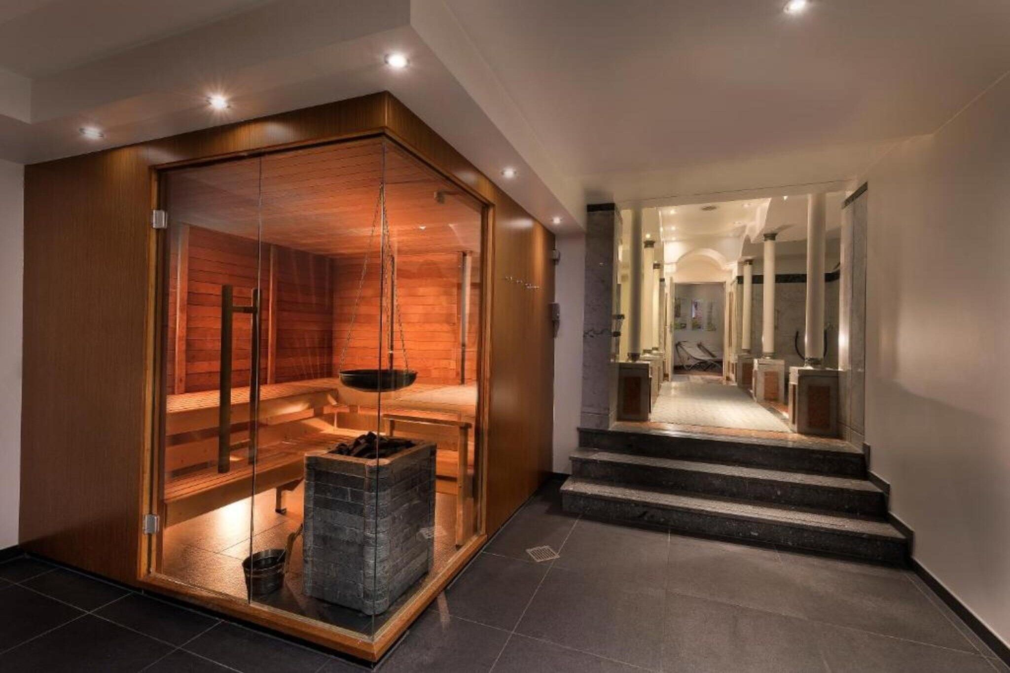 Un interior moderno con sauna, chimenea y una escalera que conduce a otra zona.