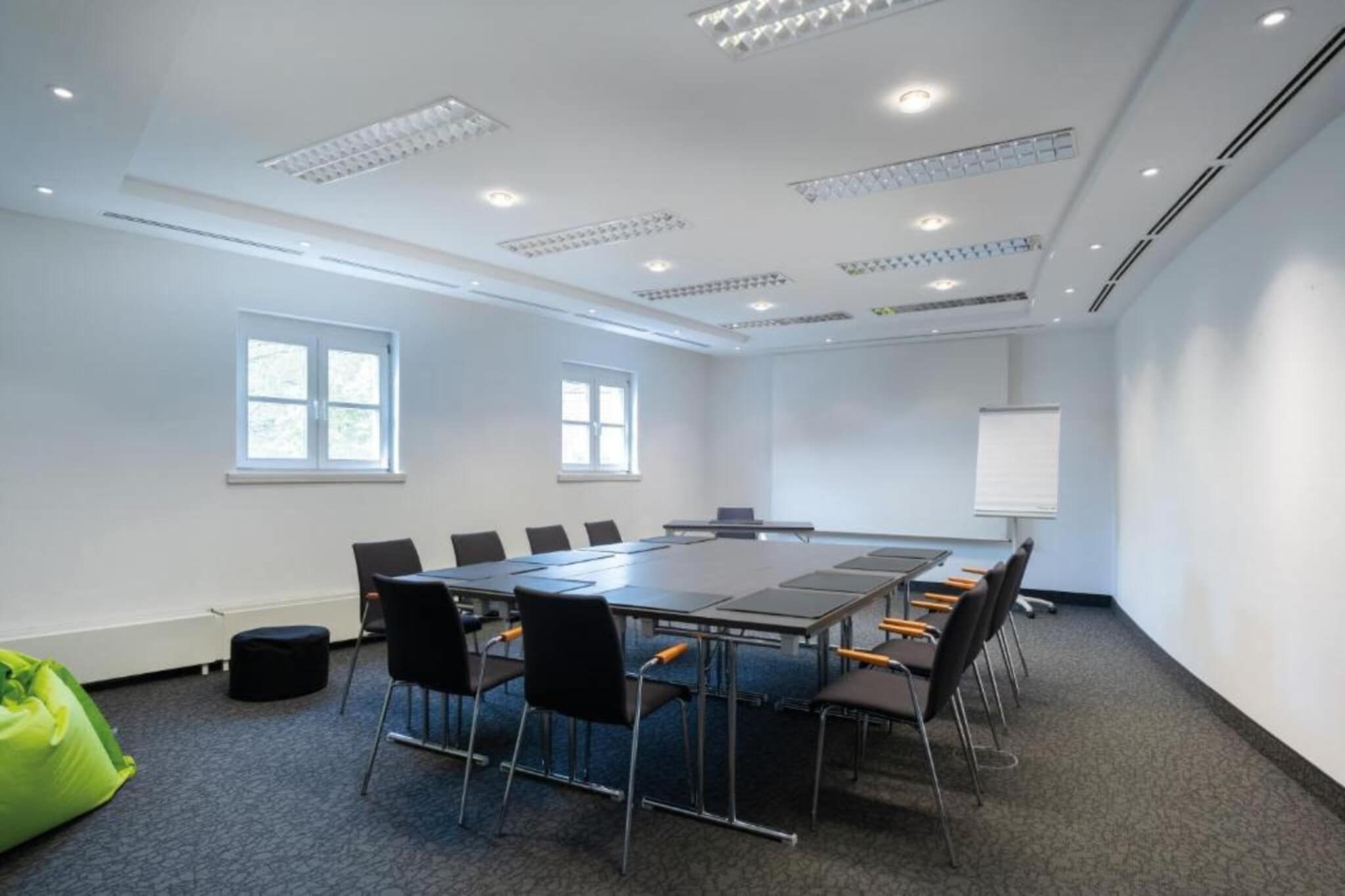 A conference room with a long table, chairs, a whiteboard, and windows.