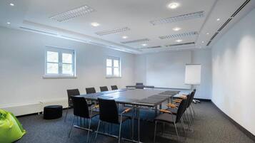 A conference room with a long table, chairs, a whiteboard, and windows.