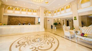 A hotel lobby with a grand chandelier, a reception desk, and a seating area with a decorative floor pattern. - Vienna International Hotel Shanghai Jiaotong Unive (Shanghai)