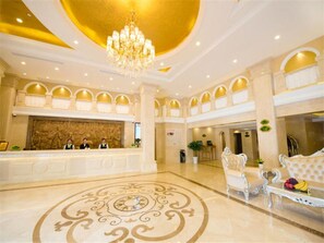 A hotel lobby with a grand chandelier, a reception desk, and a seating area with a decorative floor pattern. - Vienna International Hotel Shanghai Jiaotong Unive (Shanghai)