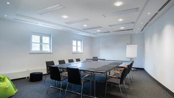 A conference room with a long table, chairs, a whiteboard, and windows.