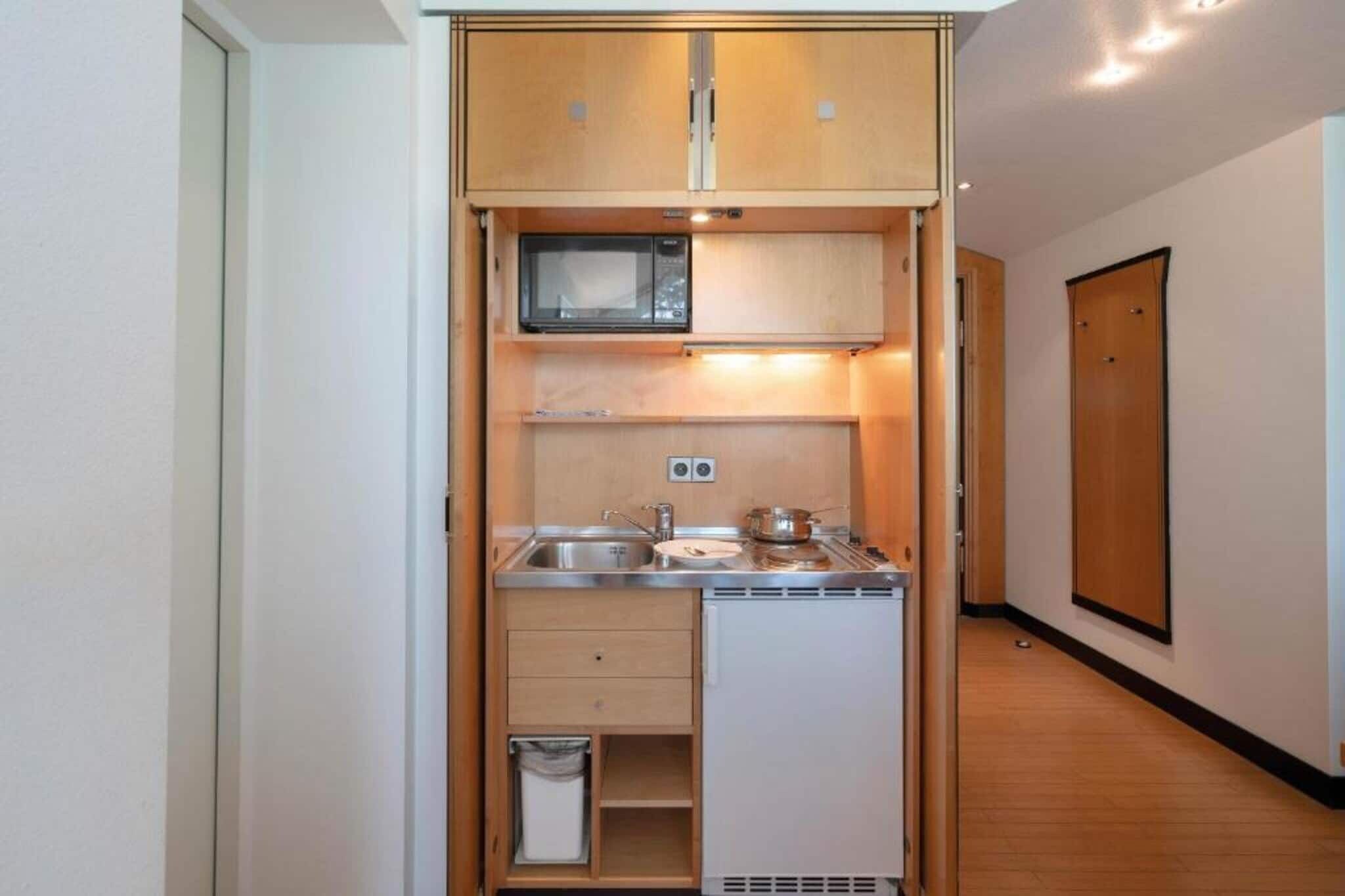 A compact kitchenette with a microwave, sink, and storage cabinets.