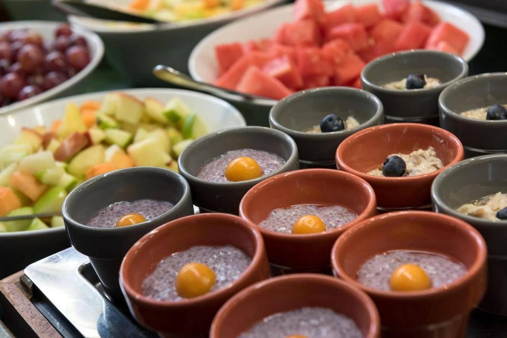 A variety of food items including bowls of chia pudding with blueberries, a plate of watermelon, and a fruit salad.