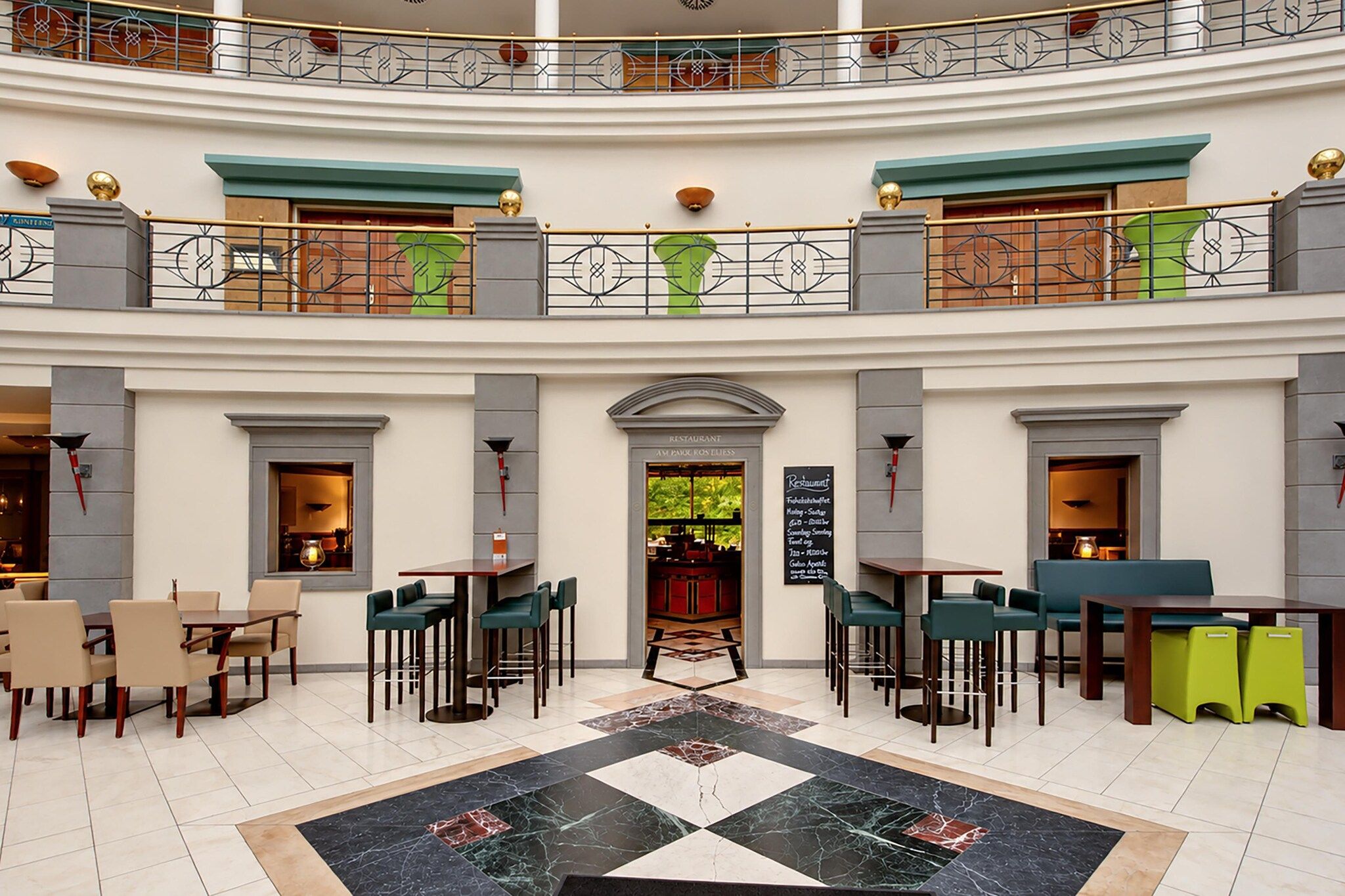 Un hall d’hôtel à plusieurs niveaux, doté d’un espace de restauration central, de plusieurs coins salon et d’un motif décoratif sur le sol.