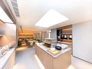 A modern kitchen with a central island, built-in appliances, and a bright overhead light. - Super 8 Hotel Xian Nan Shao Men (Xi'an)