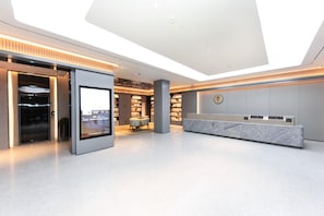 A modern hotel lobby with a reception desk, a digital display, a seating area, and a bookshelf. - Super 8 Hotel Xian Nan Shao Men (Xi'an)