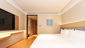 Habitación de hotel con una cama grande, una mesita de noche, un espejo y un cuadro en la pared.