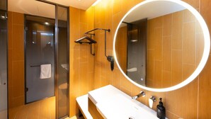 Un baño moderno con un espejo grande, revestimiento de madera en la pared, un banco y un perchero.