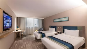 Ein Hotelzimmer mit zwei Betten, einem Schreibtisch, einem Fernseher und einem fenster mit Vorhängen.