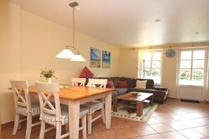 A dining area with a wooden table and chairs, a sofa, and a coffee table. - Lüttmarsch 13, Holiday Apartment 2 (Wyk auf Föhr)
