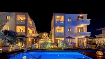 Un hotel con piscina, varios balcones y zonas de estar al aire libre.