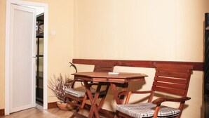 Ein Zimmer mit einem Holztisch, zwei Stühlen, einer weißen Tür und einem Regal mit Gegenst änden.