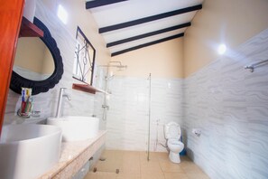 Un baño con lavamanos blanco, espejo, inodoro y ducha.