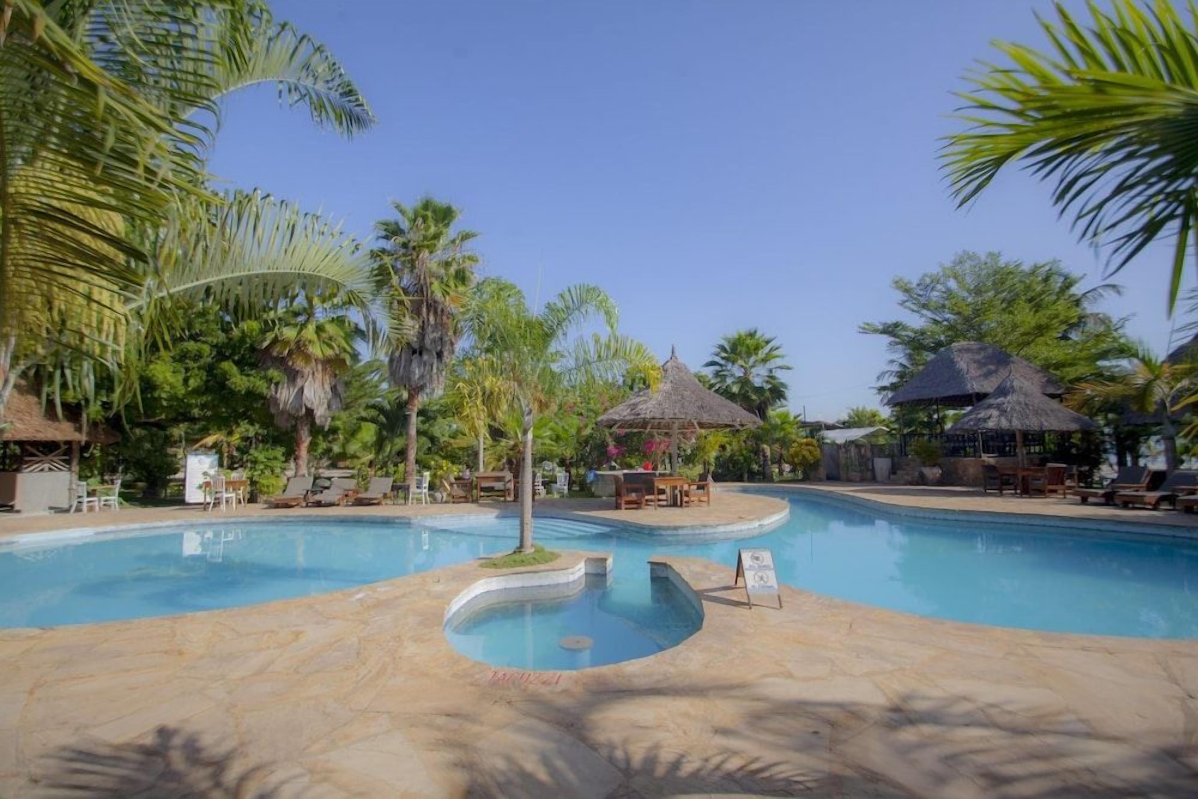 A swimming pool with lounge chairs and palm trees.