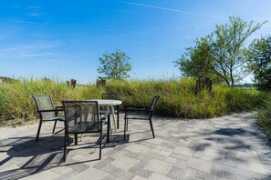 An outdoor seating area with a table and chairs, surrounded by grass and trees. - Holiday apartment 2 "Hooge" (ID 471) (Tating)