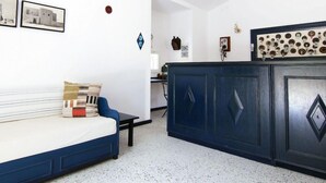 A room with a blue sofa, a small table, and a cabinet with decorative plates. - Marphe Hotel Suite And Villas (Datça)