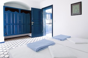 Una habitación con cama, toallas azules, pared blanca y puerta azul.