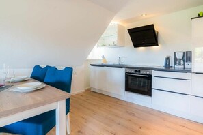 Eine moderne Küche mit weißen Schränken, einem eingebauten Backofen und einem Flachbildfernseher.