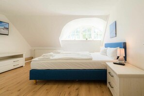 Ein Schlafzimmer mit einem Bett, einem Nachttisch, einer Lampe, einem Fenster und einer Heizung.