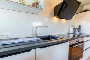 A modern kitchen with a built-in dishwasher, a stainless steel sink, and a coffee maker. - Holiday apartment 7 "Langeneß" (ID 476) (Tating)
