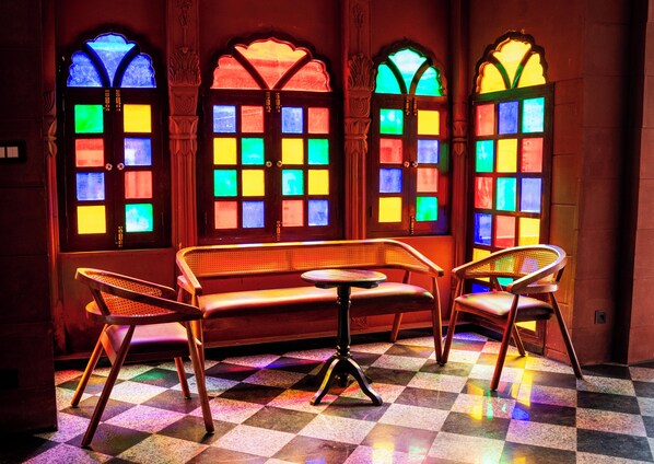 A room with a checkered floor, a bench, and two chairs.