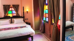 A hotel room with a bed, a nightstand, a wall-mounted lamp, and a window with curtains. - Jhalra Heritage Haveli Jodhpur (Jodhpur)