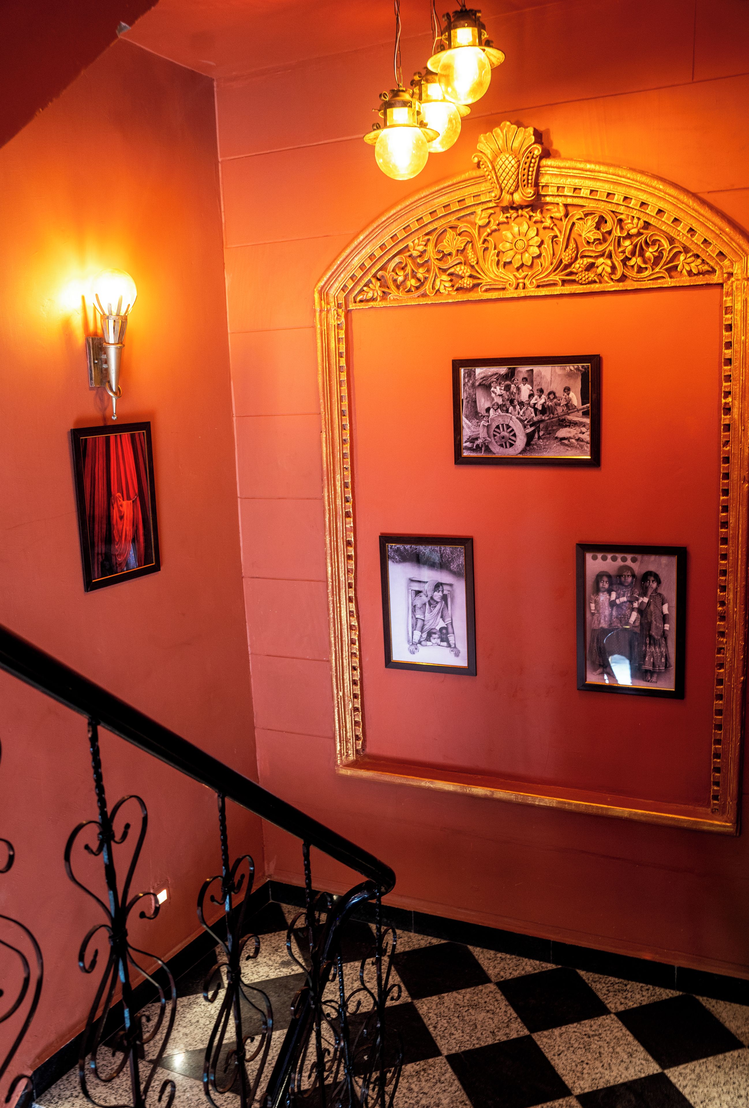 A staircase with a checkered floor, a wall with framed pictures, and a decorative golden arch.
