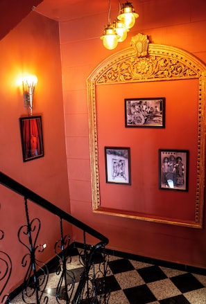 A staircase with a checkered floor, a wall with framed pictures, and a decorative golden arch.