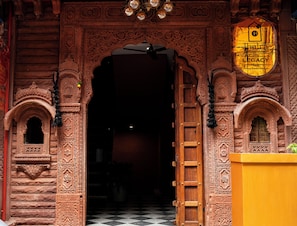 An ornate wooden entrance with intricate carvings and a sign indicating a restaurant named 'Legacy.'