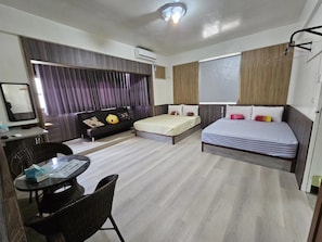 Una habitación de hotel moderna con cama, escritorio, silla y un amplio ventanal con cortinas.