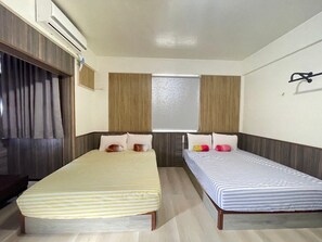 Una habitación con dos camas individuales, una mesita y un televisor instalado en la pared.