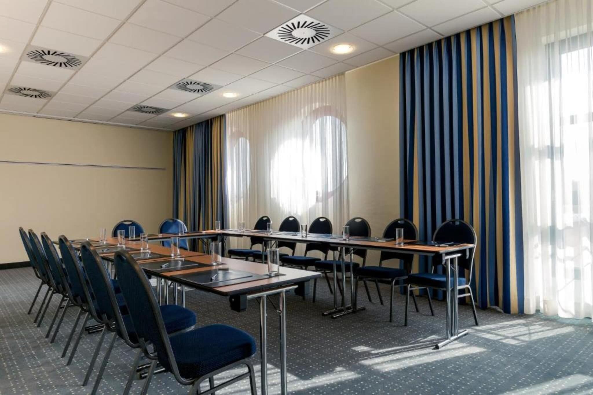 A conference room with a long table, chairs, and a projector screen.