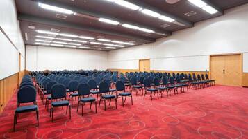 A conference room with rows of chairs, a red carpet, and a whiteboard.