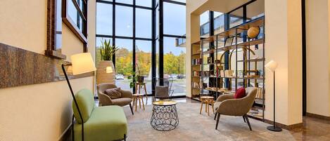 A lobby with a seating area, a bookshelf, and a large window.