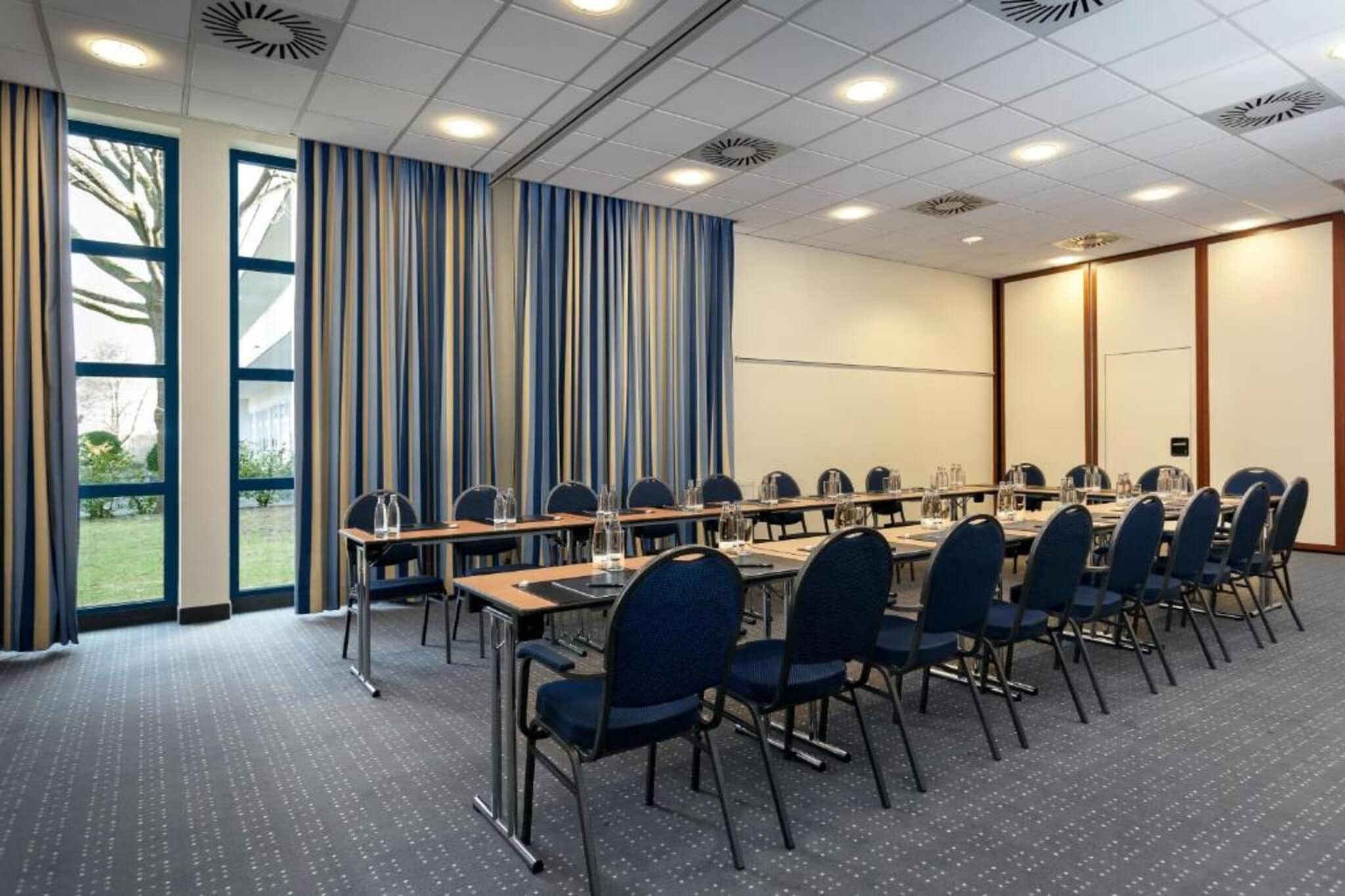 Una sala de conferències amb una taula llarga, cadires i una pantalla de projector.