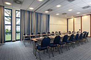 A conference room with a long table, chairs, and a projector screen.